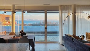 Ein modernes Wohnzimmer mit einem großen Schiebeglasfenster, das auf einen Balkon mit Solaranlage führt.
