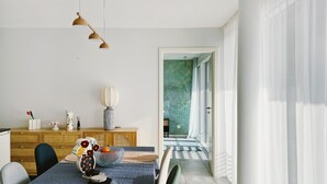 Ein stilvoller Essbereich mit Tisch für zwei Personen, einer Holzschrank und Blick in einen Raum mit ornamentalem Wandpapier.
