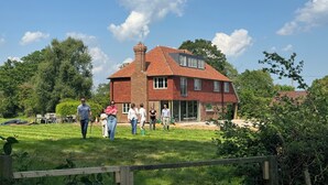 A large brick house with a prominent chimney, surrounded by lush greenery and a clear blue sky. - Large detached farmhouse in quiet Kent countryside , close to London train line (Edenbridge)