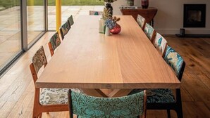 A long wooden dining table with patterned chairs, a vase with flowers, and a fireplace in the background. - Large detached farmhouse in quiet Kent countryside , close to London train line (Edenbridge)