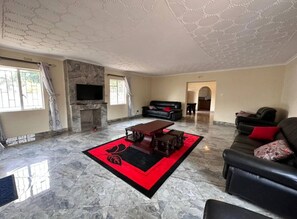 Relax in this stylish living room with a high ceiling, featuring a coffee table, sofa, and armchair.