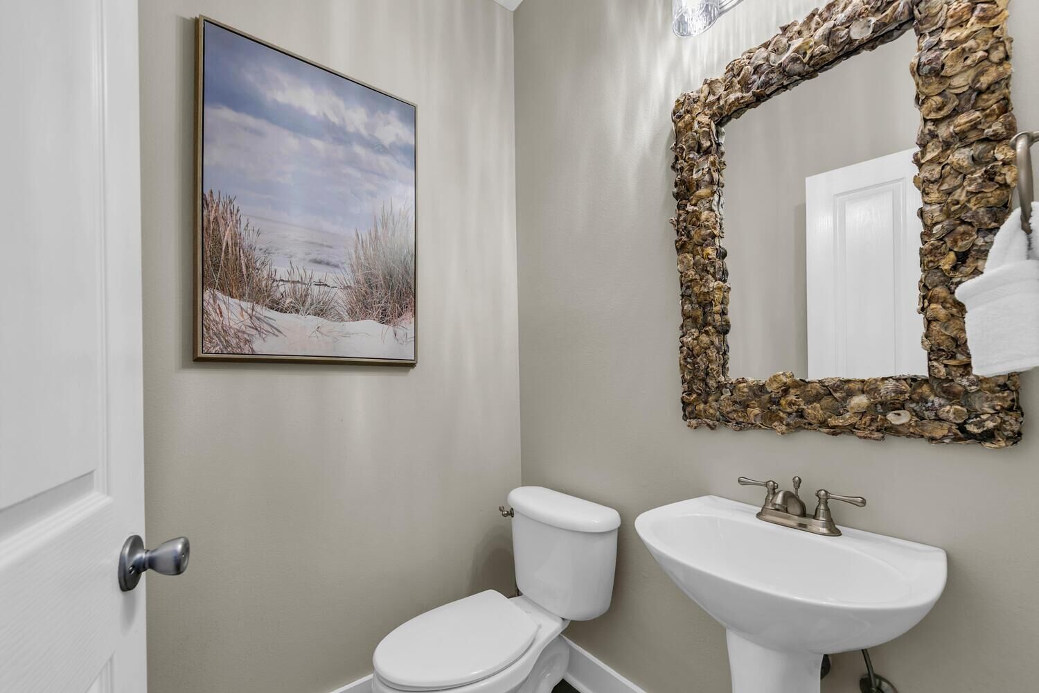 A bathroom with a toilet, sink, and a mirror framed with a stone-like border.
