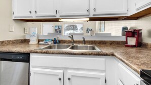 A kitchen with white cabinets, a double sink, a coffee maker, and a dishwasher. - ⭐Walk 2 Beach-Monthly Discount-1BR Sandprints A1⭐ (Miramar Beach)
