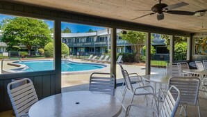 A covered outdoor area with a pool, lounge chairs, and tables. - Hidden Beach Villas 122 - A Sunset Paradise (Santa Rosa Beach)