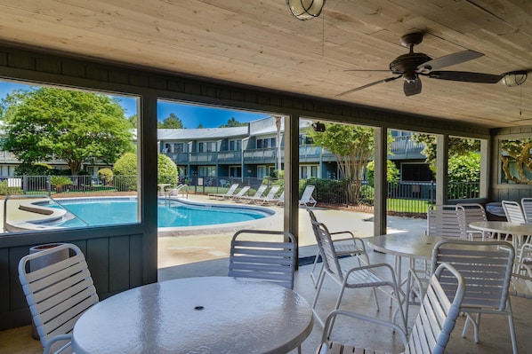 A covered outdoor area with a pool, lounge chairs, and tables. - Hidden Beach Villas 122 - A Sunset Paradise (Santa Rosa Beach)