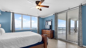 Une chambre avec un lit, un ventilateur de plafond, une commode, une télévision et un balcon donnant sur la mer.