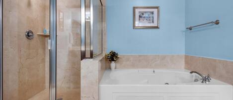 Une salle de bain avec une douche à parois de verre, une baignoire blanche et un mur bleu.