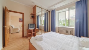 A bedroom with a bed, a TV, a wardrobe, and a window with curtains.