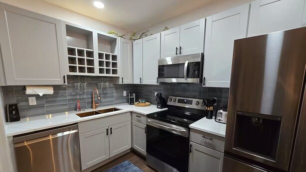 A modern kitchen with white cabinets, stainless steel appliances, and a blue rug.