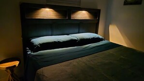 A bed with a dark headboard and two illuminated panels above it.