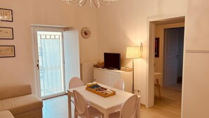 A compact living space with a dining area, a television, and a chandelier. - Dimora Agnese Deluxe Apartment (Lecce)