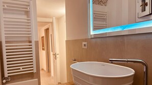 Un baño moderno con una bañera independiente, un espejo y un perchero para toallas.