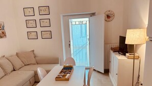 Una sala de estar acogedora con sofá, mesa de comedor con sillas, lámpara y vistas al exterior.