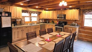 Una cocina de estilo cabaña de madera con una isla central, armarios de madera y una zona de comedor con seis sillas.