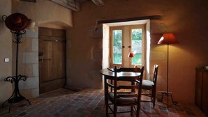 A rustic dining area with a wooden table and chairs, a lamp, and a view through a window. - Domaine du Ris de Feu (Chalais)