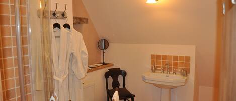 A bathroom with a shower, a sink, a chair, and a mirror.