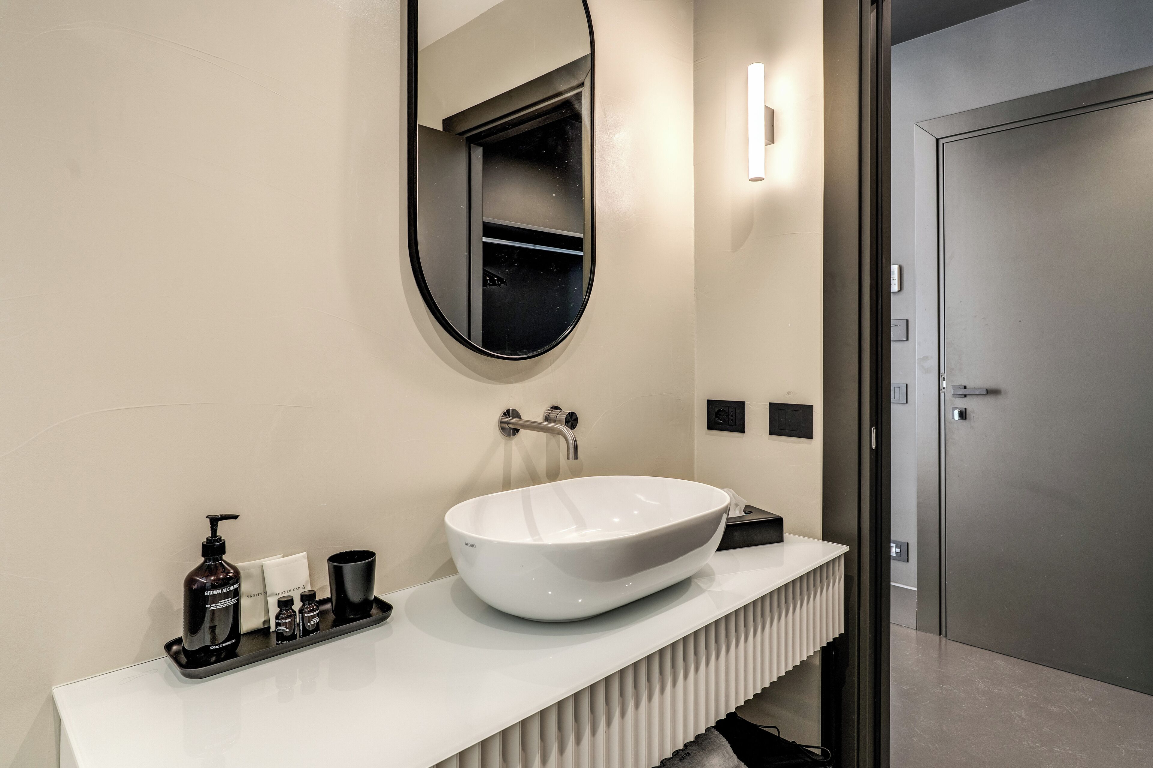 A modern bathroom with a large oval sink, a mirror, and a white countertop.