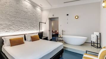 Ein modernes Hotelzimmer mit einem großen Bett, einer Badewanne und einer kleinen Sitzecke am Pool.