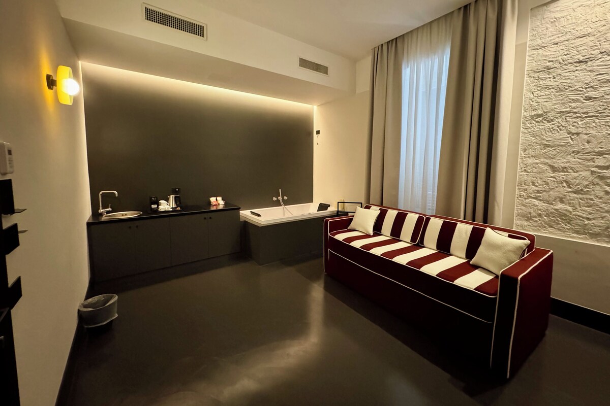 A modern bathroom with a sofa, two sinks, and a large mirror.
