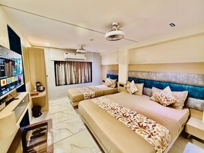A hotel room with two beds, a TV, a desk, and a ceiling fan. - Hotel RV Residency (Ahmedabad)