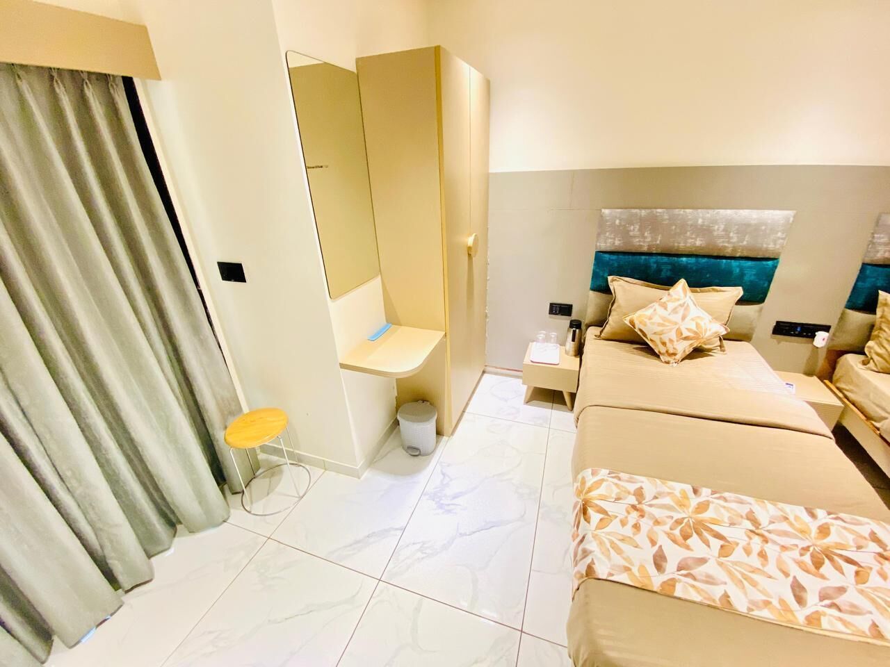 Een hotelkamer met een bed, een klein tafeltje, een stoel, een spiegel en een kledingkast.