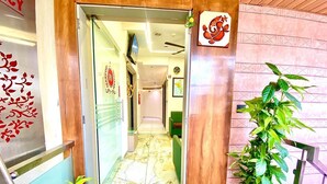 A hotel entrance with a green carpet, a potted plant, and a sign with a fish symbol. - Hotel RV Residency (Ahmedabad)