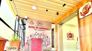 A hotel entrance with a wooden ceiling, a green artificial turf floor, and a signboard welcoming guests to RV Residency. - Hotel RV Residency (Ahmedabad)