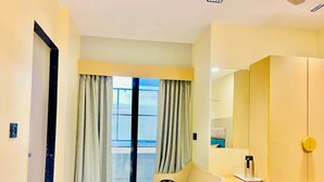 A hotel room with a bed, a small table, a chair, a wardrobe, and a window with curtains. - Hotel RV Residency (Ahmedabad)