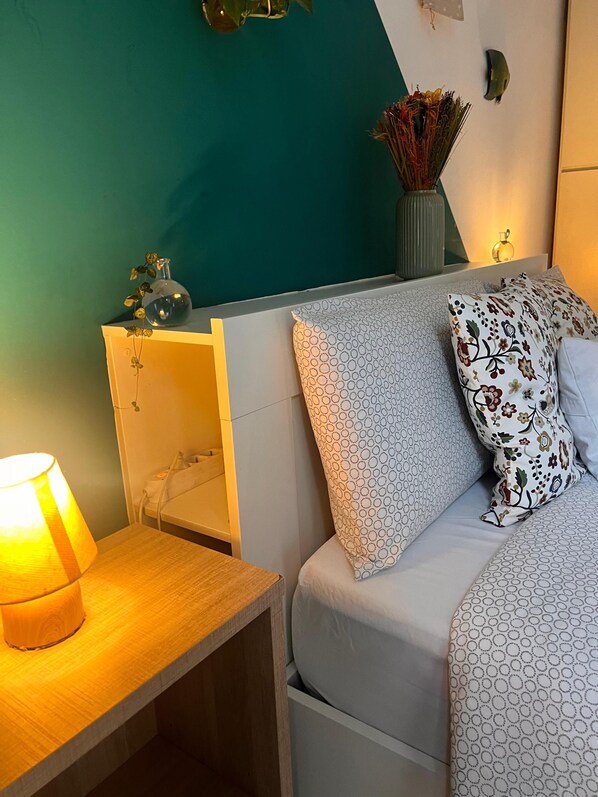 A neatly arranged bedroom with a bed, a bedside table with a lamp, and a wall-mounted shelf with decorative items. - 10 minutes from the Duomo LA TERRAZZA SU MILANO offers a moment of tranquility (Milano)