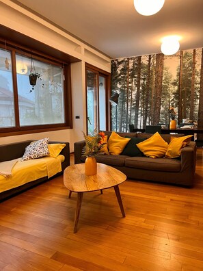 A modern living room with a sofa set, a coffee table, and a large window with a forest view. - 10 minutes from the Duomo LA TERRAZZA SU MILANO offers a moment of tranquility (Milano)