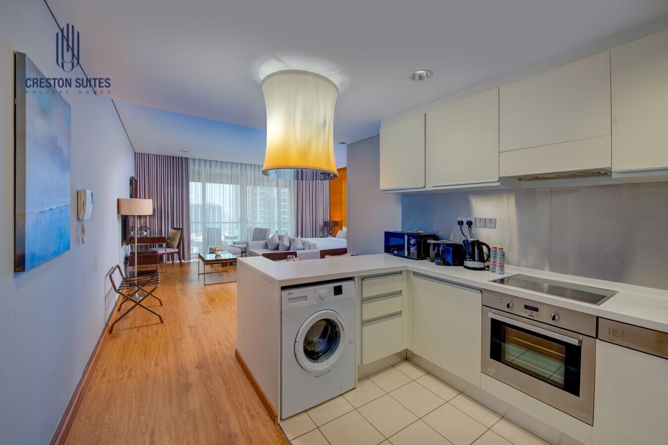 Ein modernes Hotelzimmer mit Waschmaschine, Küchenzeile und Essbereich.