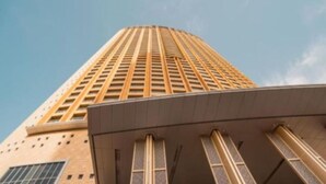 Un edificio alto con un diseño arquitectónico moderno, que presenta una serie de líneas verticales y ventanas rectangulares.