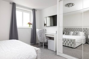 A bedroom with a bed, a desk, a chair, a mirror, and a window with curtains. - Elegant Flat with Balcony (Edinburgh)