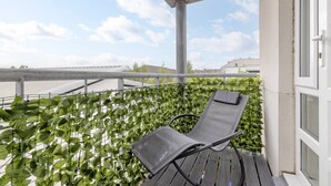 A balcony with a metal chair, a metal railing, and a view of buildings in the background. - Elegant Flat with Balcony (Edinburgh)