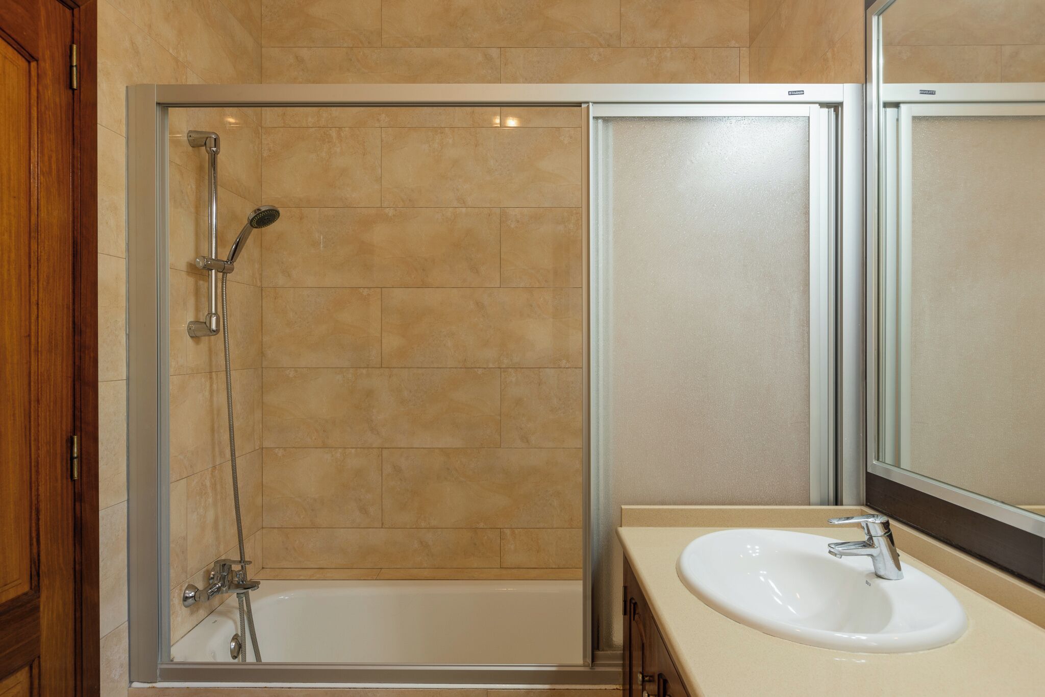 A bathroom with a glass-enclosed shower, a bathtub, and a sink with a mirror above it.