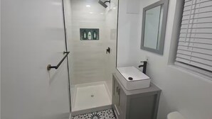 Un bagno moderno con box doccia in vetro, lavandino bianco e water.