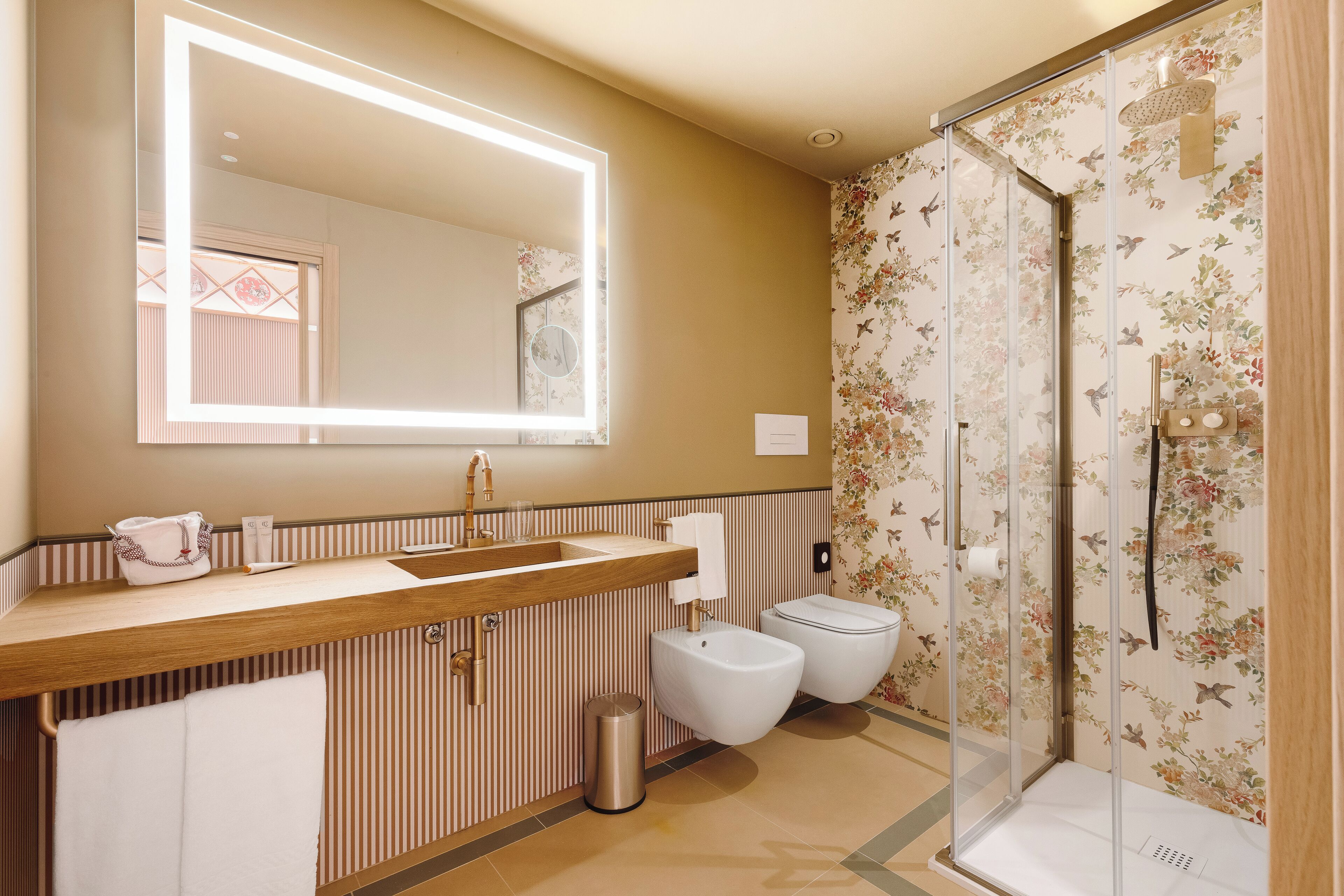 Un baño con tocador de madera, un espejo grande, cabina de ducha y retrete.