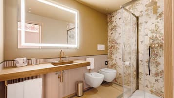 Un baño con tocador de madera, un espejo grande, cabina de ducha y retrete.