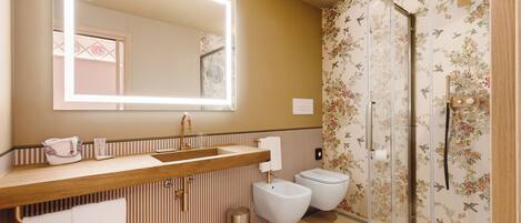 A bathroom with a wooden vanity, a large mirror, a shower enclosure, and a toilet.