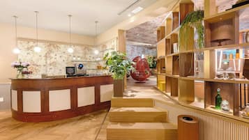 A modern reception area with a wooden counter, a potted plant, and a staircase leading to a second floor.