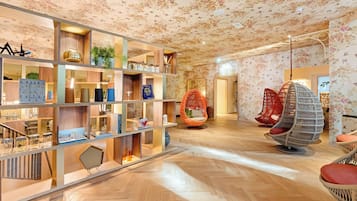 Een modern interieur met houten vloeren, een centraal wandmeubel met diverse objecten en kleurrijke hangstoelen.