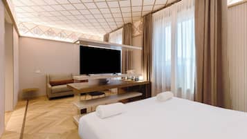 Een moderne hotelkamer met een groot bed, een flatscreen televisie, een bank en een bureau met een computer.