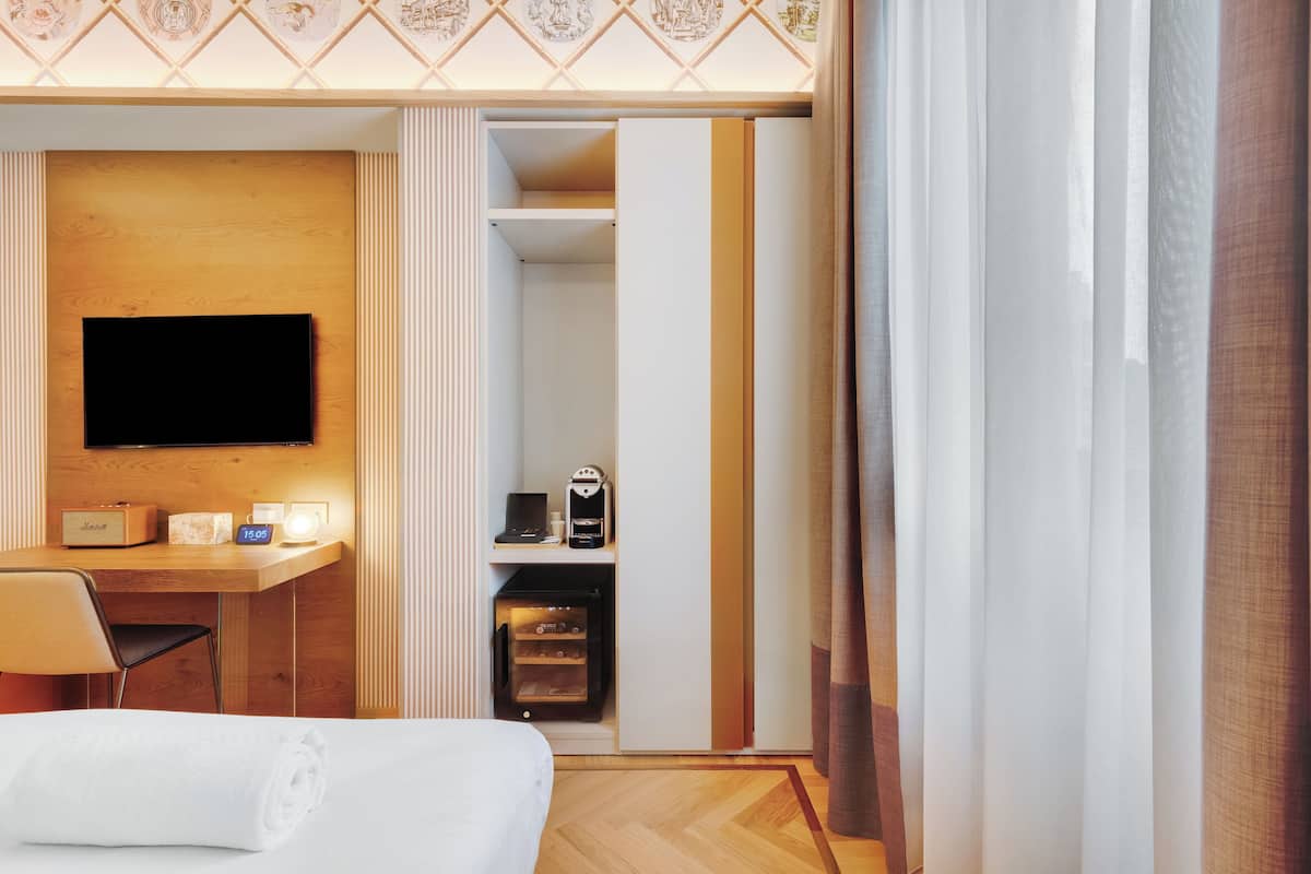 Une chambre d’hôtel équipée d’un lit, d’un bureau avec un téléviseur à écran plat, d’une machine à café et d’un mini-bar.