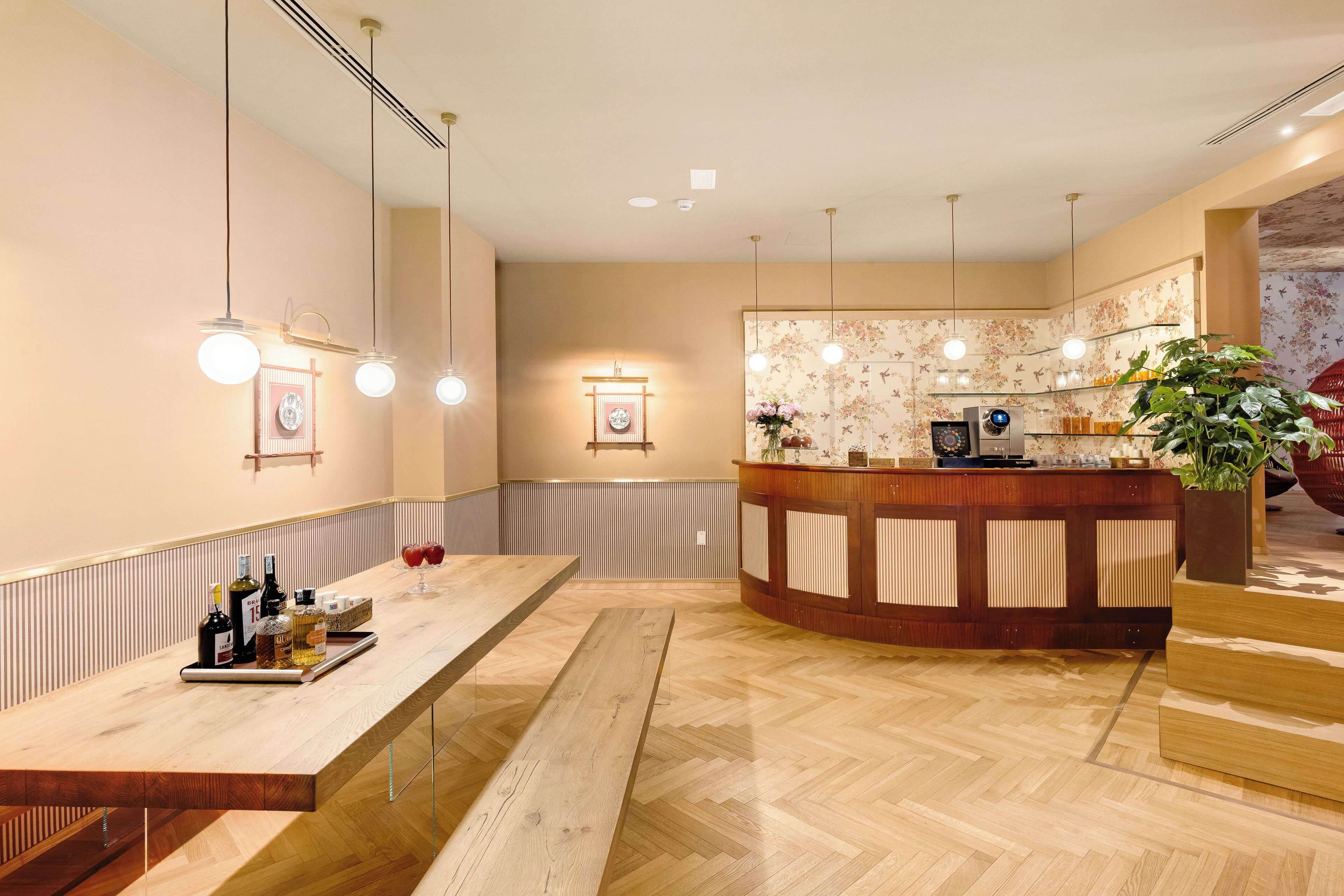 A modern reception area with a wooden reception desk, a counter with a digital screen, and a large potted plant.