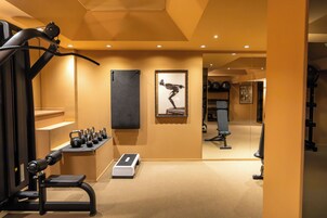 Een fitnessruimte met trainingsapparatuur, een loopband en een spiegel.