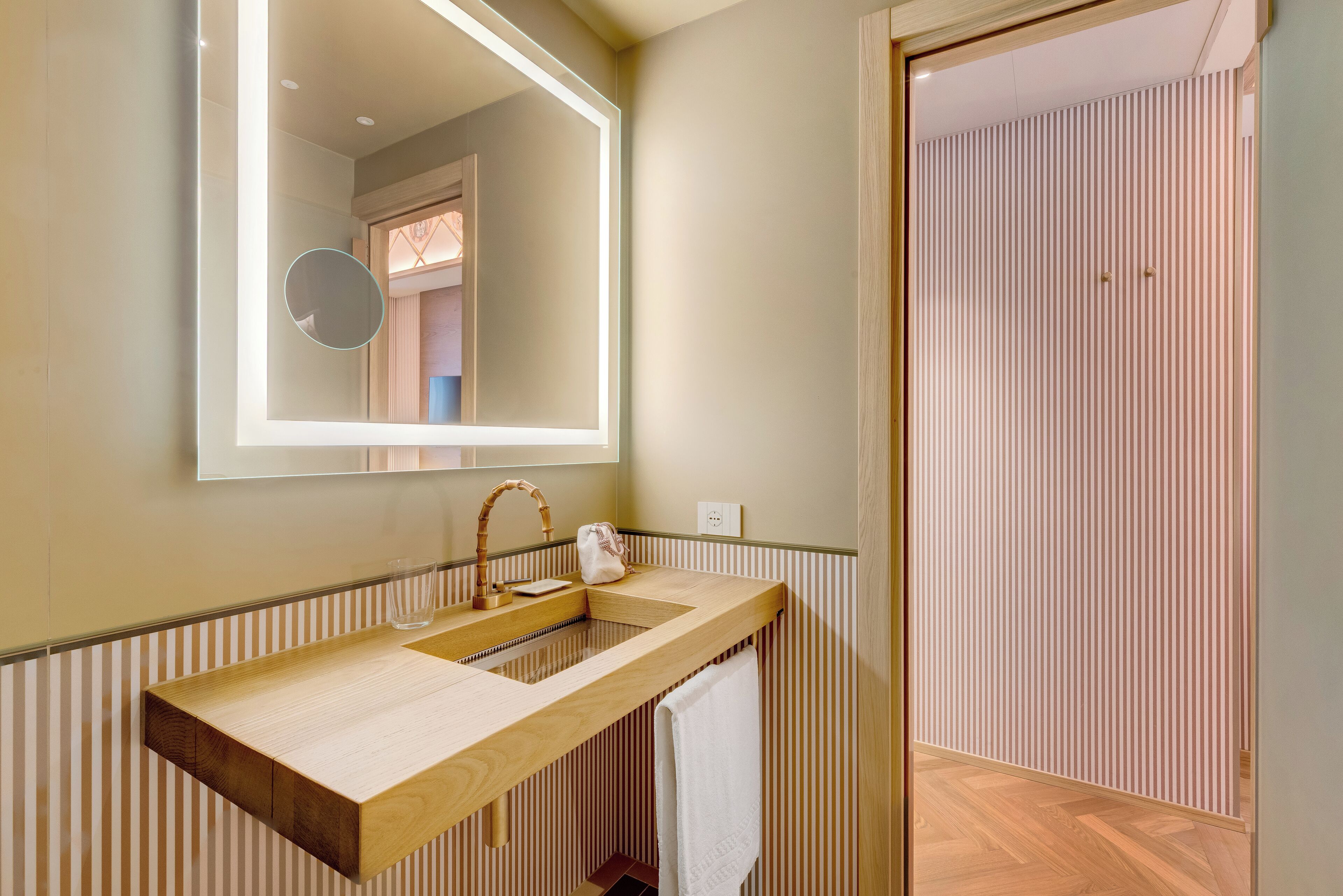 Ein modernes Badezimmer mit einem Holzlagerfläschchen, einem großen Spiegel und einer gestreiften Wand.