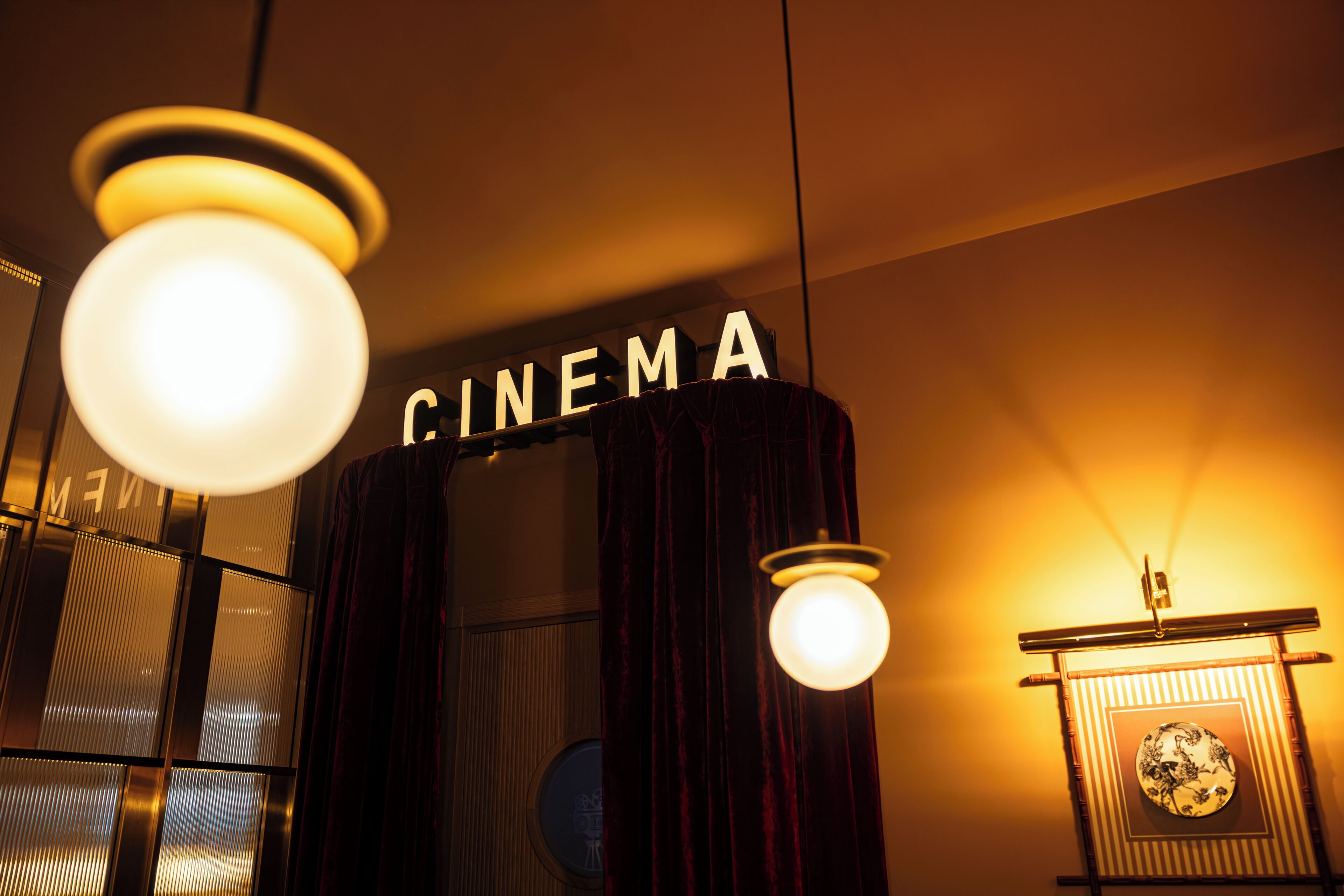 A cinema sign, a round light fixture, and a framed picture on a wall.