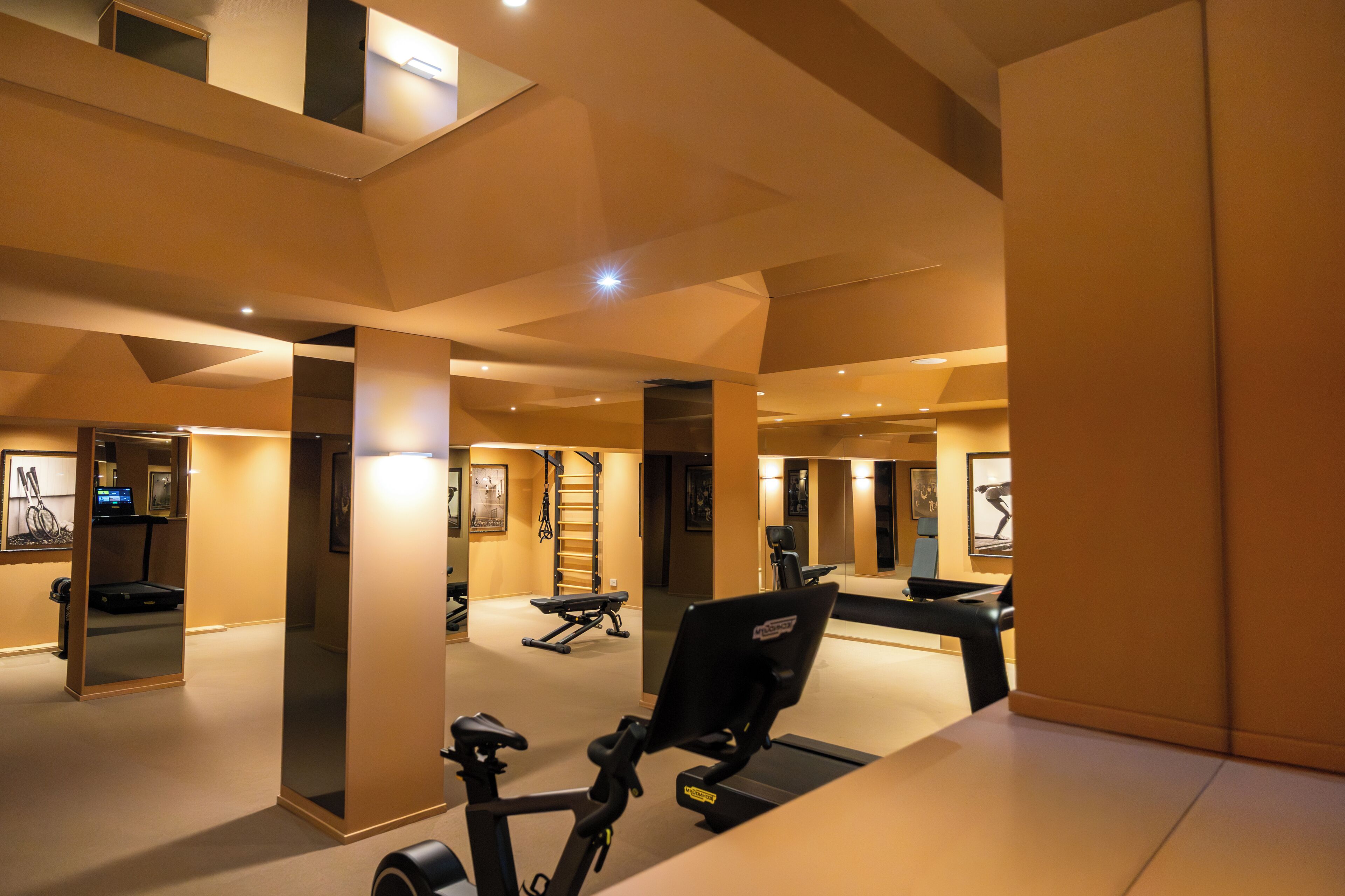 Une salle de sport équipée de matériel d’exercice, d’un tapis de course et d’un mur recouvert de miroirs.
