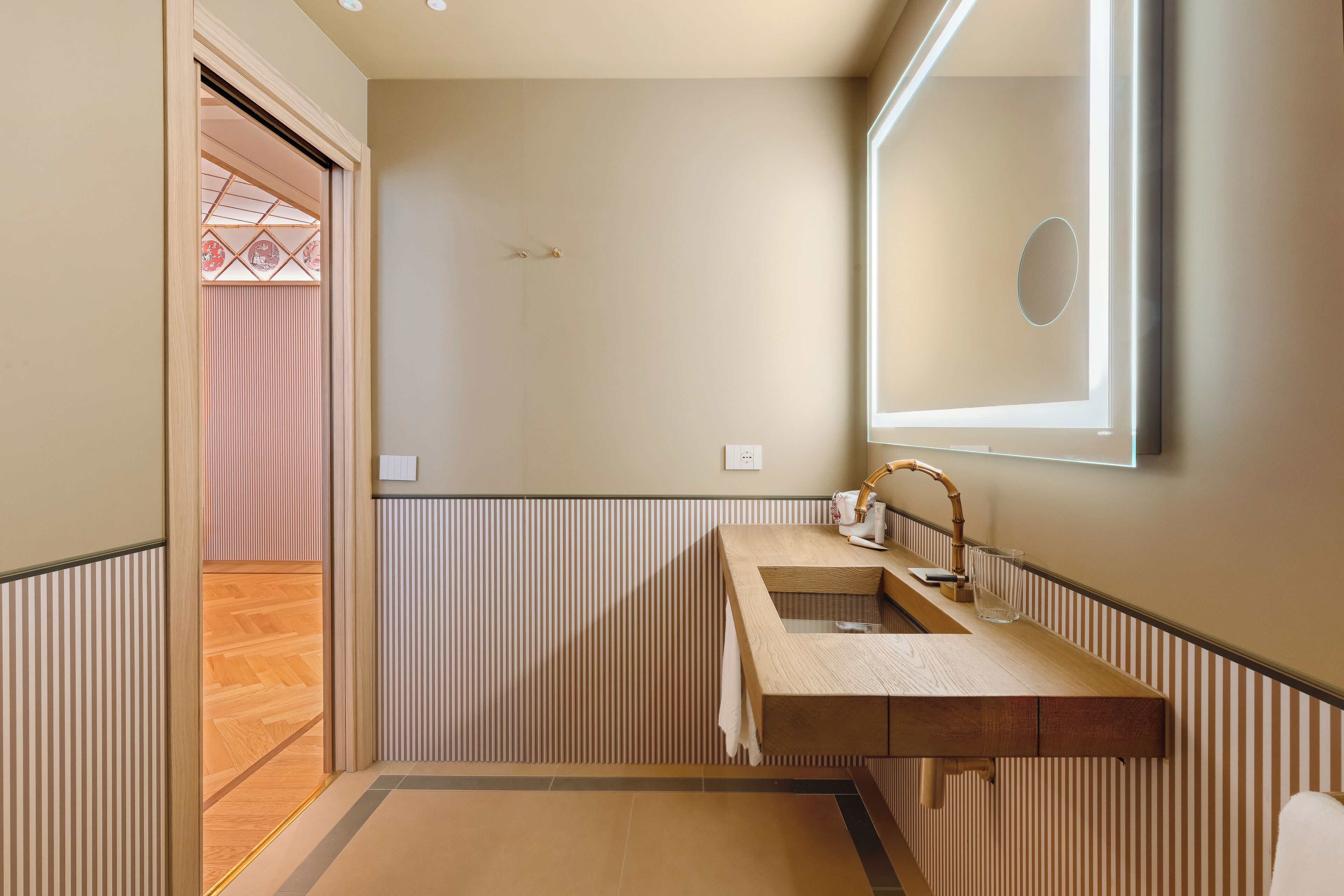 Un bagno con un mobile bagno in legno, uno specchio e un asciugamano appeso al muro.