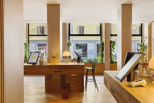 Een moderne receptiebalie met een digitaal scherm, een lamp en een stoel.
